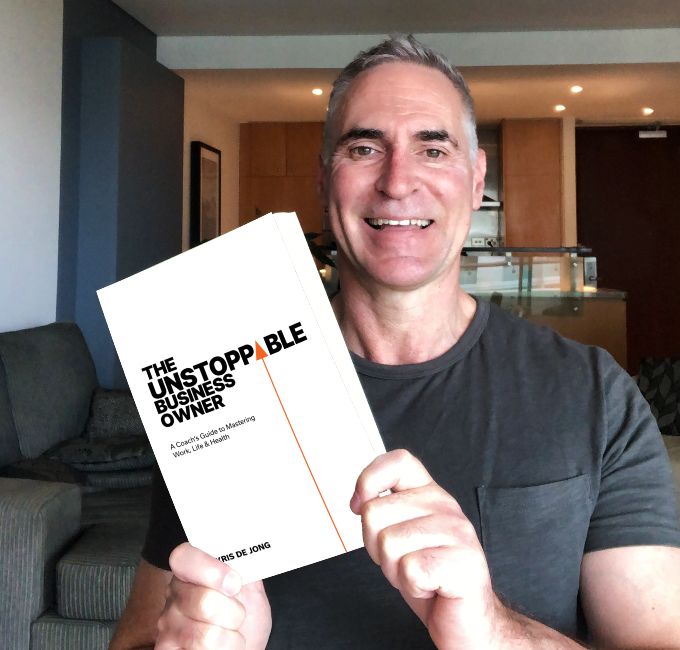 Kris de Jong holding his book for business owners - The Unstoppable Business Owner